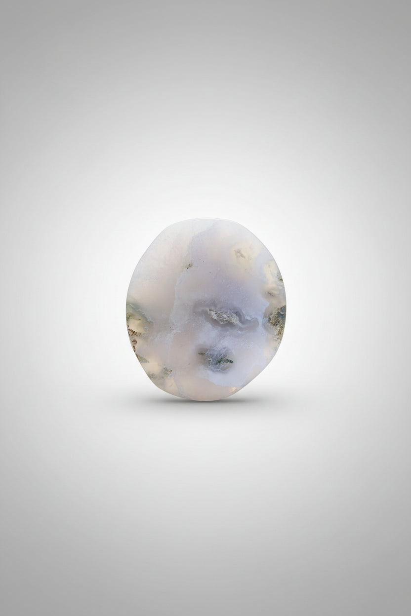 A smooth, polished white stone with natural cloudy inclusions, resting on a dark brown wooden tabletop.