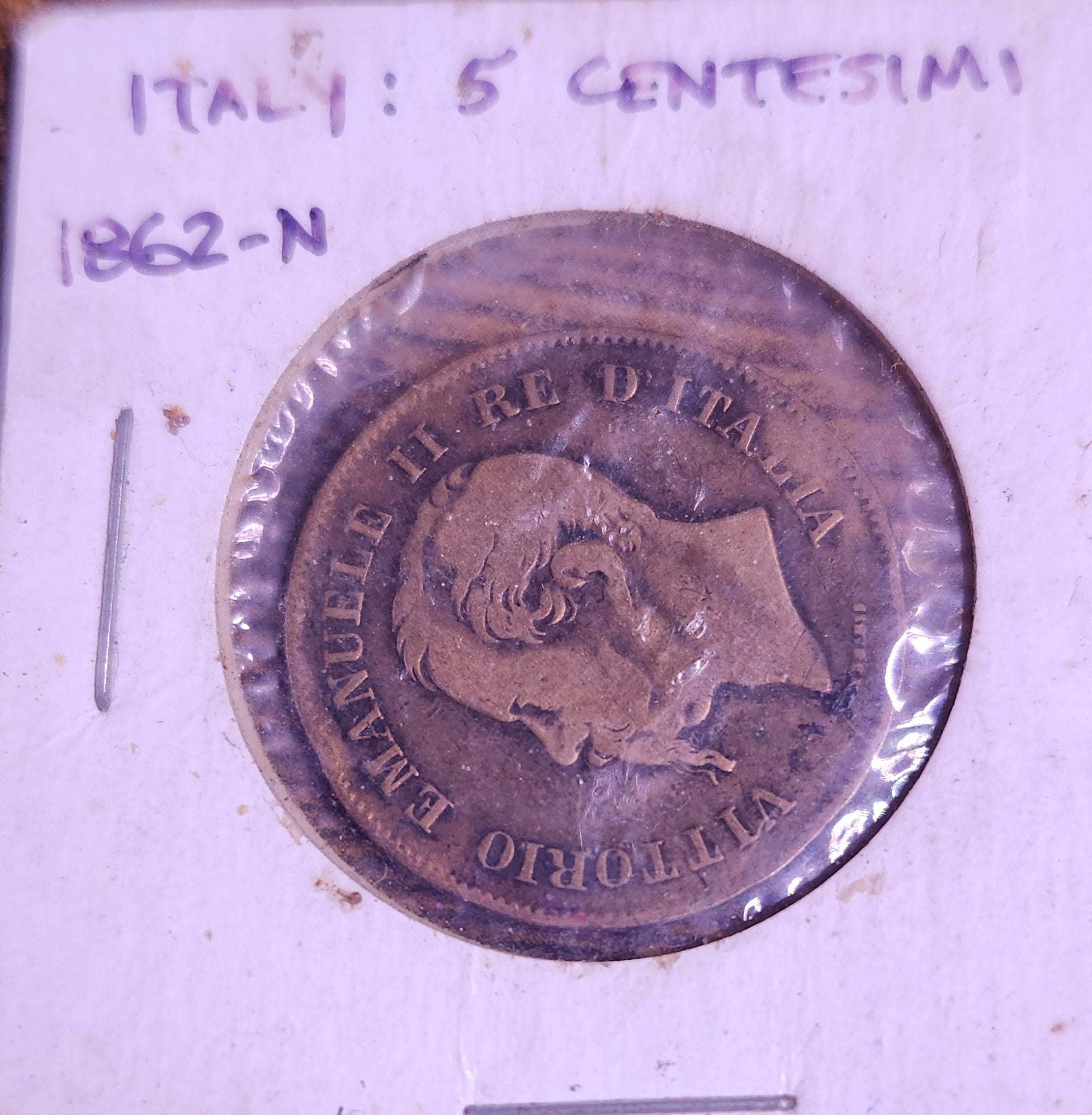 Old coin with detailed design on a wooden surface