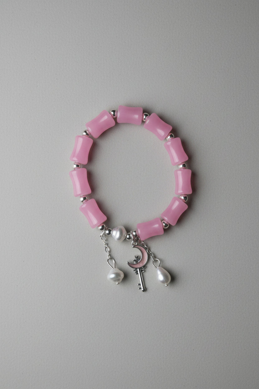 Pink beaded bracelet with silver accents on a gray fabric background