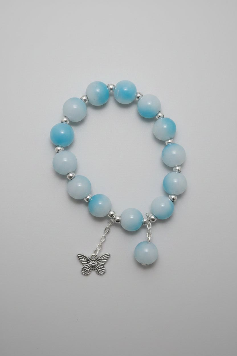 Bracelet with light blue beads and a silver charm on a neutral background