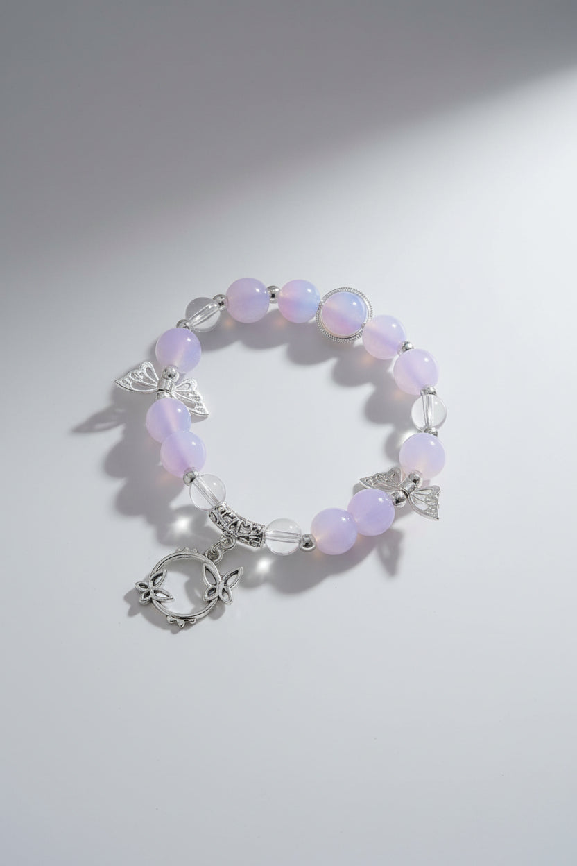 Bracelet with pink beads and silver butterfly charms on a light gray background