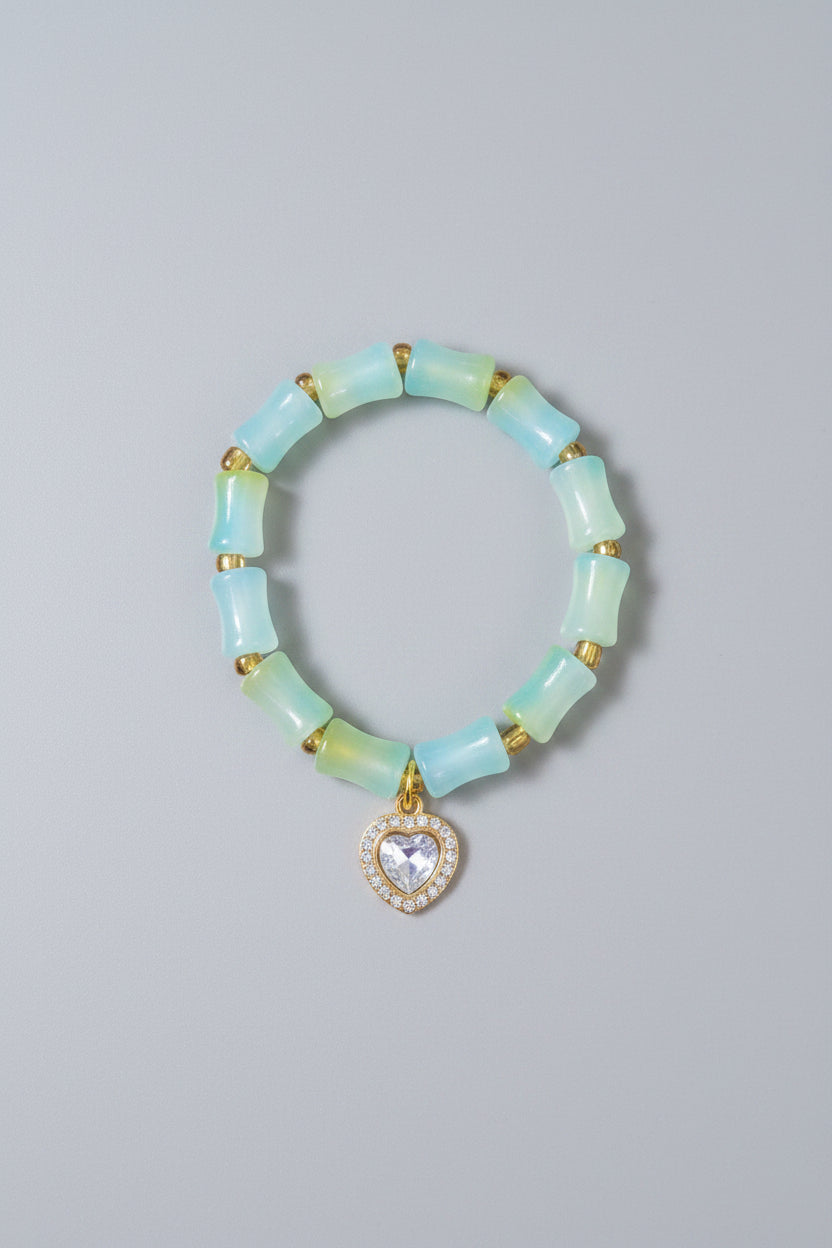 Green beaded bracelet with a heart-shaped charm on a gray background