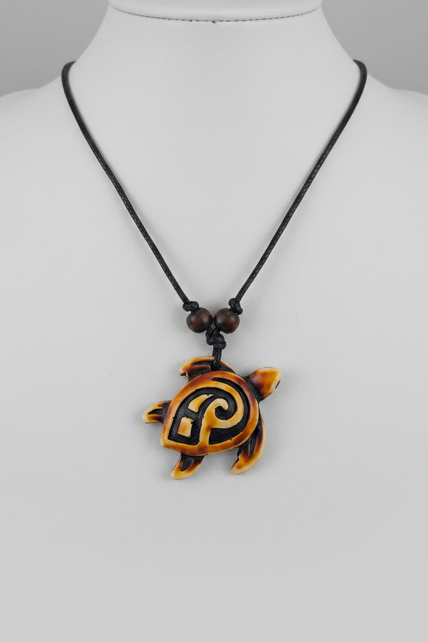A turtle-shaped pendant necklace with a black cord, displayed on a white mannequin neck. The pendant is primarily orange with black swirl patterns and small yellow accents.