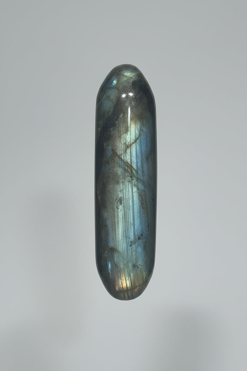 a polished labradorite stone cylinder, showing its characteristic gray-green body with a blue flash and natural inclusions