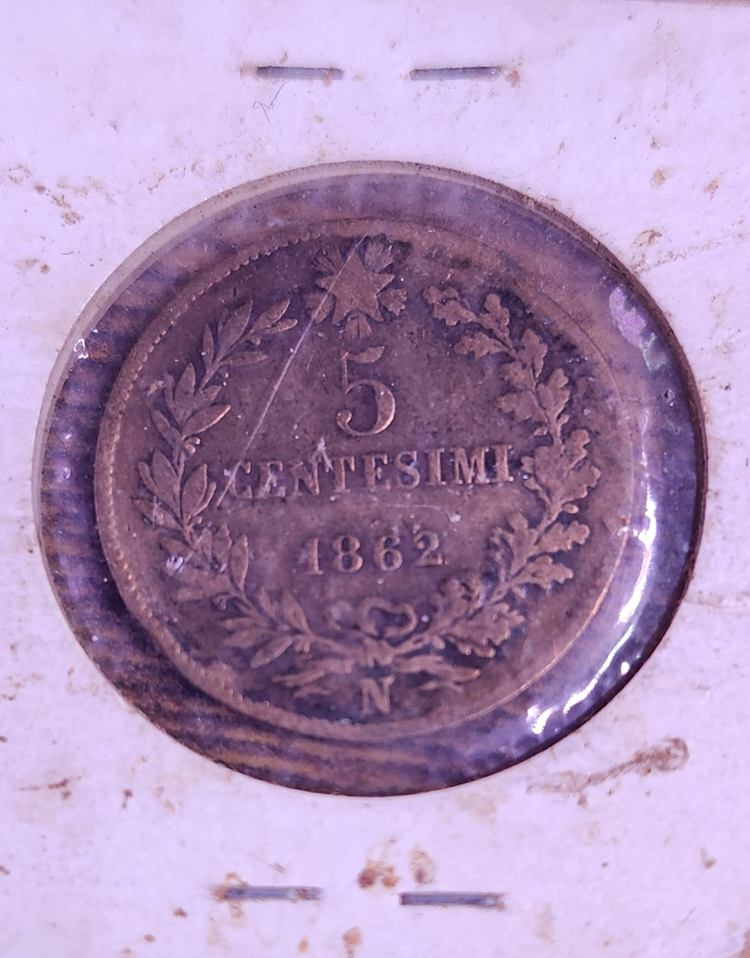 Old coin on a white card with a wooden surface