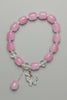 Pink beaded bracelet with a silver clasp on a gray fabric background
