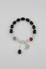 Black beaded bracelet with charms on a gray fabric background