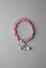 Pink beaded bracelet with silver accents on a gray fabric background