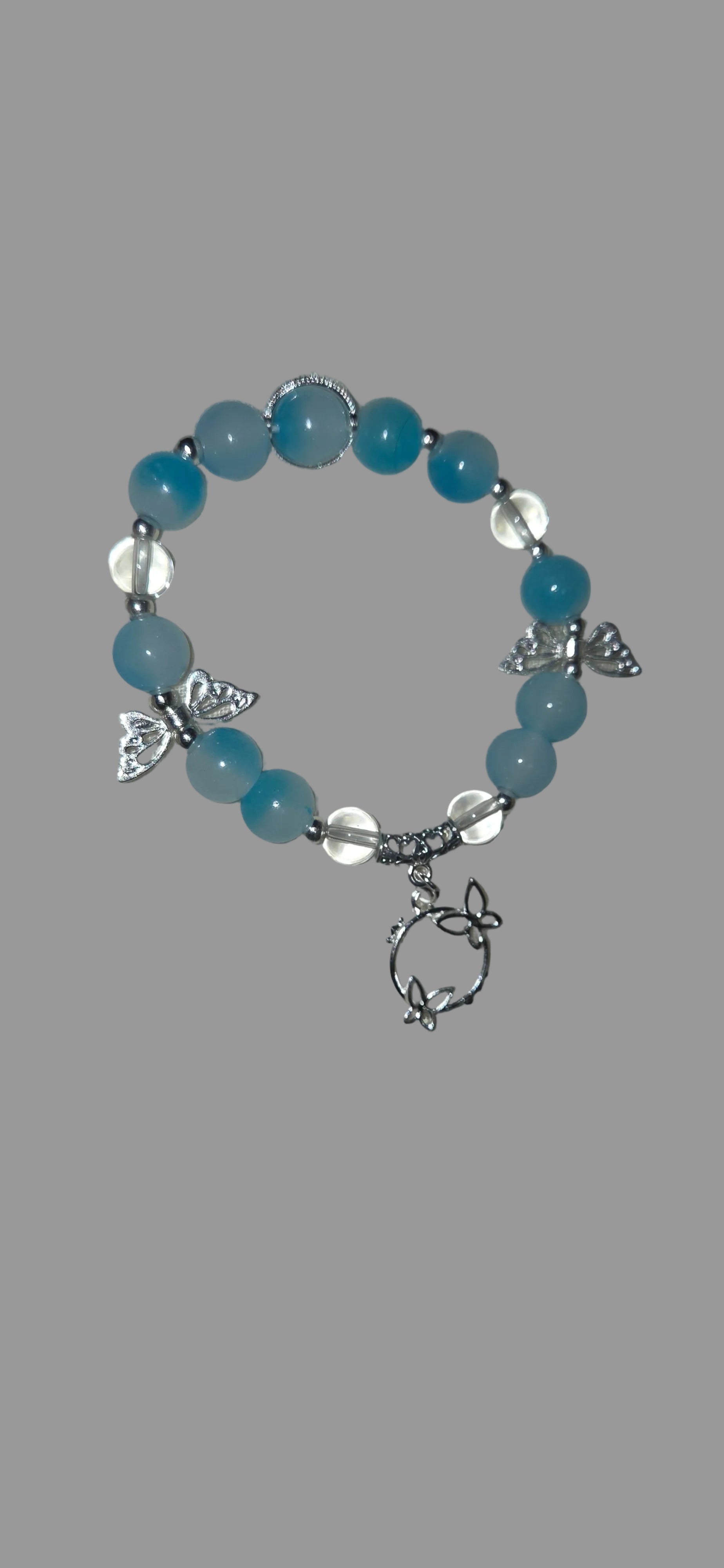 Bracelet with blue beads and silver butterfly charms on a gray fabric background