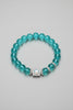 Turquoise beaded bracelet with a silver clasp on a gray background