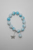 Bracelet with light blue beads and a silver charm on a neutral background