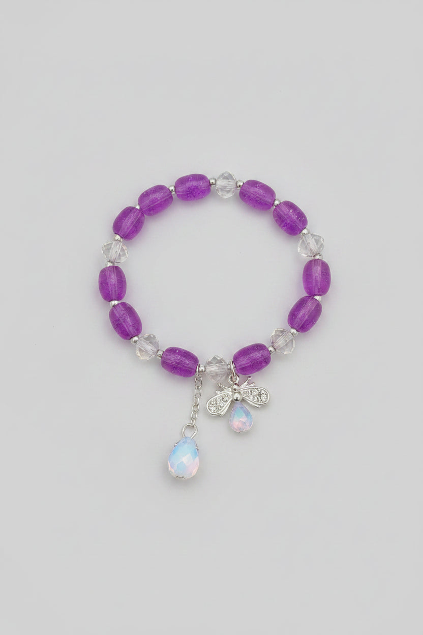 Pink beaded bracelet with a bow and bee charm on a light gray background