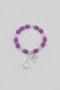Pink beaded bracelet with a bow and bee charm on a light gray background