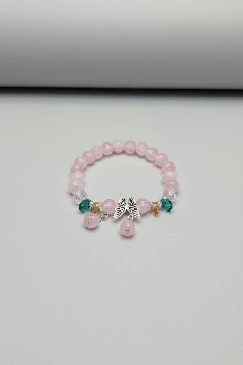 Pink beaded bracelet with charms on a white background