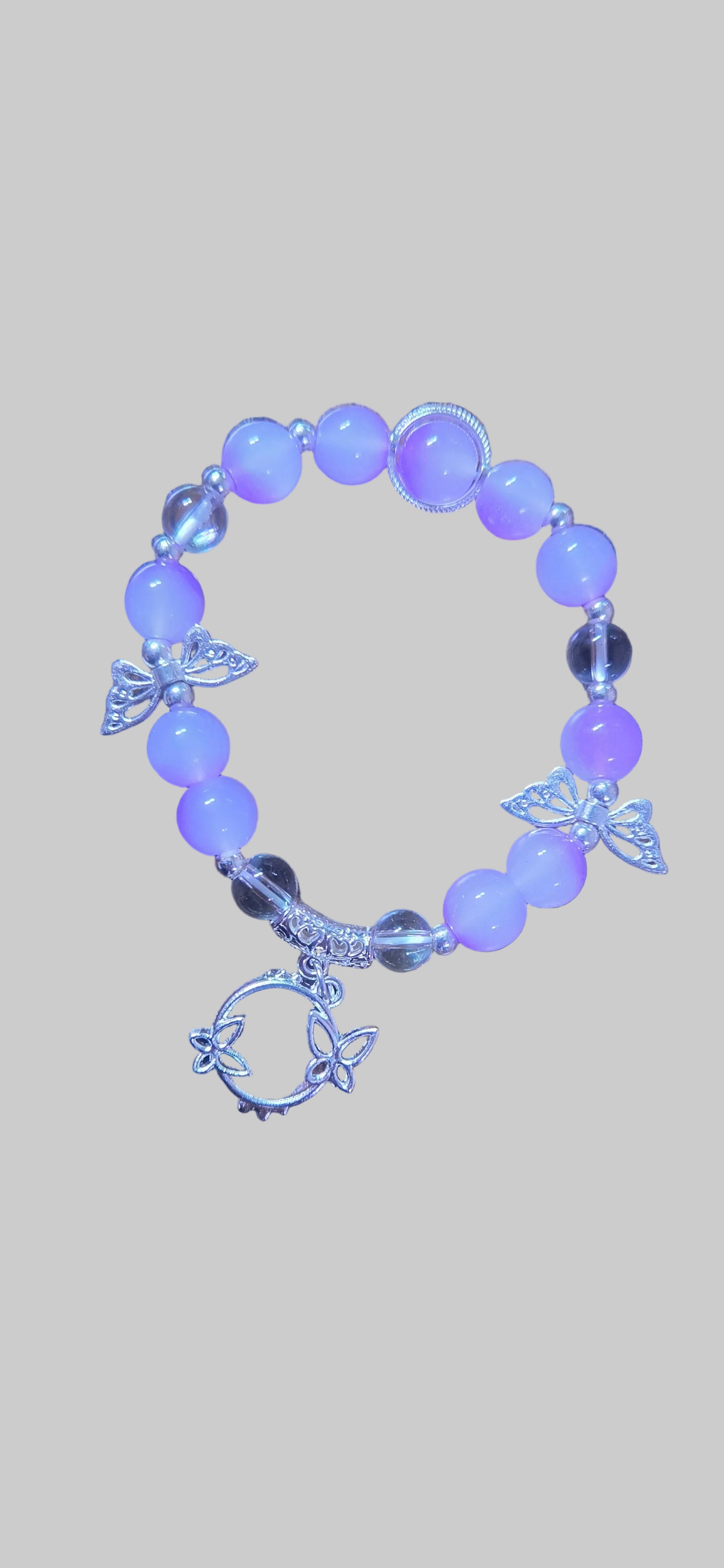 Purple beaded bracelet with butterfly charms on a light gray background