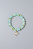 Green beaded bracelet with a heart-shaped charm on a gray background