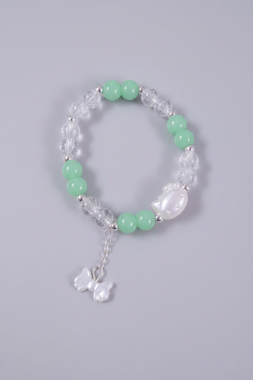 Bracelet with green beads and a cat bead with a bow charm on a gray background