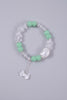 Bracelet with green beads and a cat bead with a bow charm on a gray background