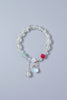 Light green beaded bracelet with colorful charms on a light gray background