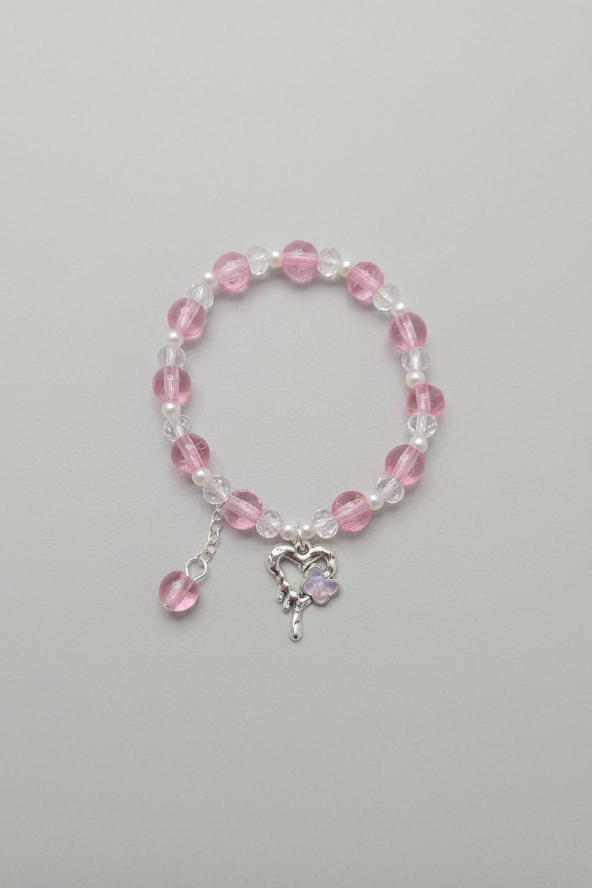 Beaded bracelet with pink and clear beads and a silver charm on a gray background
