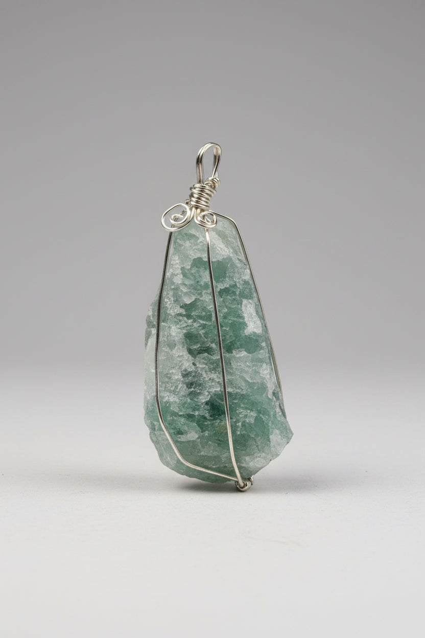 A raw green stone pendant wrapped in silver-colored wire
