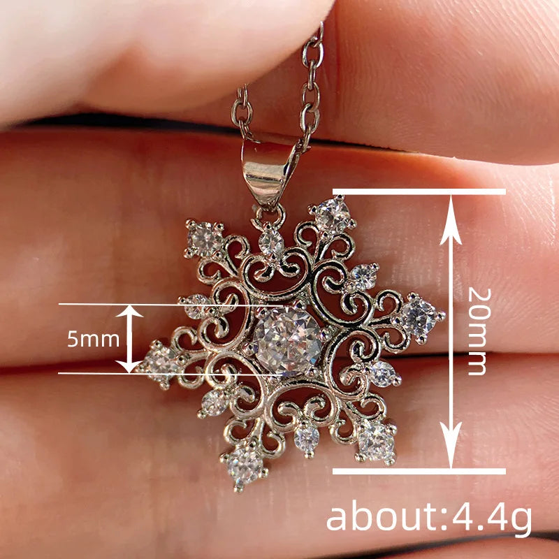 Silver snowflake pendant held between fingers with measurements displayed